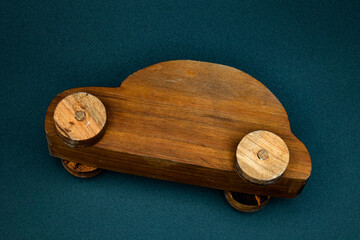 wooden toy car made from cherry wood, isolated on a black background, crashed on its side, top view