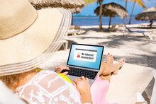 Woman Relaxing On Remote Beach While On Vacation And Using Laptop Computer With An Error Message On The Screen Showing No Internet Connection Available