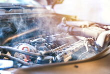 Car Engine Overheating Close Up. Vehicle Engine In Smoke. Smoke Or Steam From A Vehicle Engine