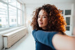 © Westend61 - Young woman with curly hair taking selfie
