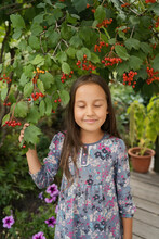 Smiling Girl With Eyes Closed Standing Under Viburnum Tree