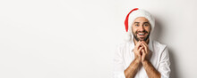 Party, Winter Holidays And Celebration Concept. Excited And Hopeful Man In Santa Hat Looking At Christmas Gift With Amazement, White Background