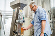 © djoronimo - Man filling wine from storage tank in winery.