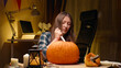 Preparing pumpkin for Halloween. Woman sitting and carving with knife halloween Jack O Lantern pumpkin at home for her family.