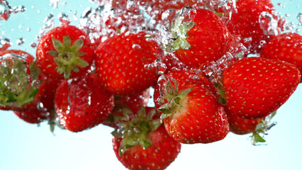 Wall Mural - Strawberries pieces falling underwater on white background.