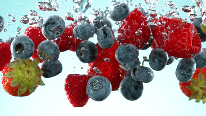 Wall Mural - Berries fruit pieces falling underwater on blue background.