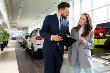 Wall Mural - an employee of a car dealership helps to sort out a car insurance buyer woman