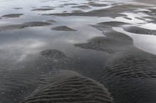 Puddles And Undulations In The Sand Caused By The Outgoing Tide