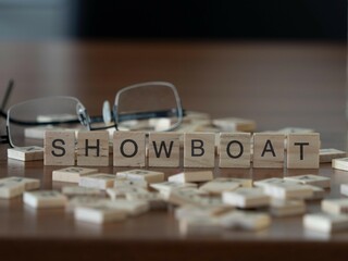 showboat word or concept represented by wooden letter tiles on a wooden table with glasses and a book