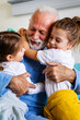 © NDABCREATIVITY - Happy laughing grandfather playing, having fun with his grandchildren together.