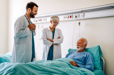 Wall Mural - Doctor consulting happy senior man patient on hospital bed. Healthcare and medical insurance concept