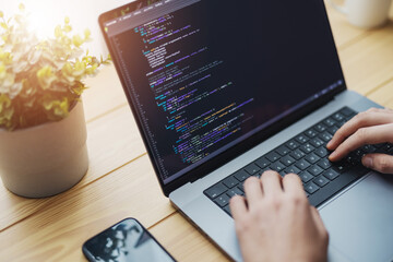 Man coding on laptop on a desk, remote working from home