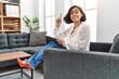 © Krakenimages.com - Young hispanic therapist woman working at consultation office smiling with an idea or question pointing finger with happy face, number one