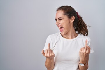 Poster - Beautiful brunette woman standing over isolated background showing middle finger doing fuck you bad expression, provocation and rude attitude. screaming excited