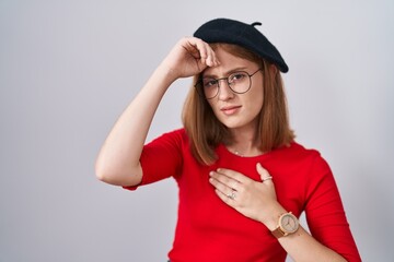 Wall Mural - Young redhead woman standing wearing glasses and beret touching forehead for illness and fever, flu and cold, virus sick