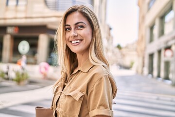 Wall Mural - Young blonde girl smiling happy standing at the city.