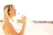 Beautiful woman drinks water. Young happy woman at the beach.