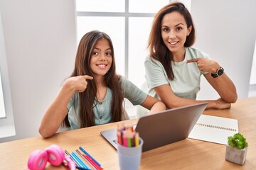 Canvas Print - Young mother and daughter doing homework at home pointing finger to one self smiling happy and proud