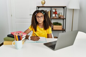 Poster - Young african american girl doing homework at home relaxed with serious expression on face. simple and natural looking at the camera.