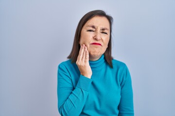 Sticker - Middle age hispanic woman standing over isolated background touching mouth with hand with painful expression because of toothache or dental illness on teeth. dentist