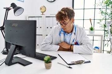 Wall Mural - Young caucasian doctor man working at the clinic with hand on stomach because indigestion, painful illness feeling unwell. ache concept.