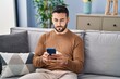 © Krakenimages.com - Young hispanic man using smartphone sitting on sofa at home