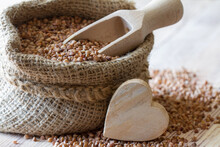 Buckwheat In Jute Sack With Heart Of Wood On Wooden Background, Healthy Heart Food Concept 