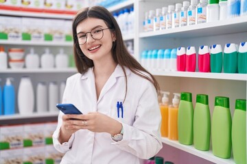 Sticker - Young caucasian woman pharmacist using smartphone working at pharmacy