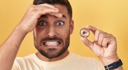 Poster - Handsome hispanic man holding uniswap cryptocurrency coin stressed and frustrated with hand on head, surprised and angry face