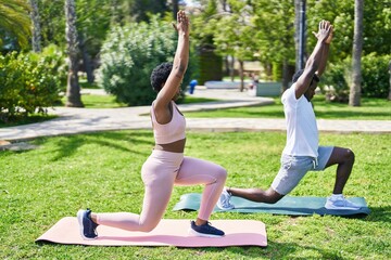 African american man and woman couple doing yoga exercise at park