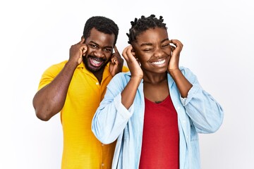 Poster - Young african american couple wearing casual clothes covering ears with fingers with annoyed expression for the noise of loud music. deaf concept.