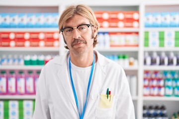 Poster - Caucasian man with mustache working at pharmacy drugstore relaxed with serious expression on face. simple and natural looking at the camera.