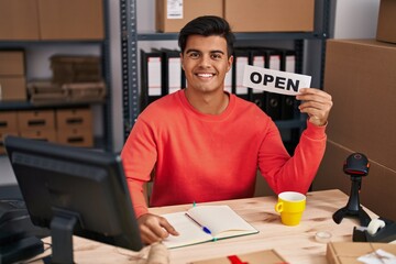 Sticker - Hispanic man working at small business ecommerce holding open banner looking positive and happy standing and smiling with a confident smile showing teeth