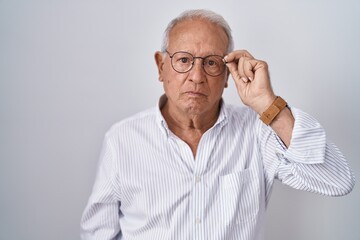 Sticker - Senior man with grey hair holding glasses with hand thinking attitude and sober expression looking self confident