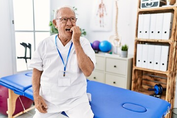 Sticker - Senior physiotherapy man working at pain recovery clinic looking stressed and nervous with hands on mouth biting nails. anxiety problem.