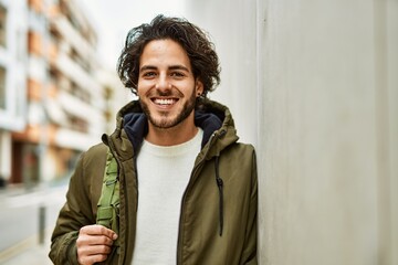 Sticker - Handsome hispanic man smiling leaning on the wall