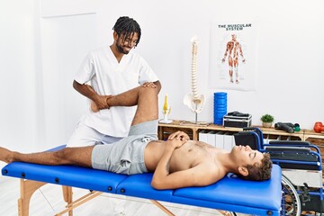 Poster - Two men physiptherapist and patient having rehab session stretching leg at clinic