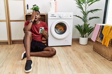 Canvas Print - Young african american man using smartphone waiting for washing machine yawning tired covering half face, eye and mouth with hand. face hurts in pain.