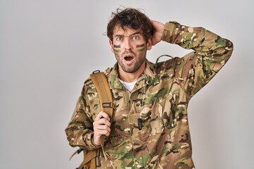 Canvas Print - Hispanic young man wearing camouflage army uniform crazy and scared with hands on head, afraid and surprised of shock with open mouth