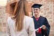 © Krakenimages.com - Man and woman mother and son standing together holding graduate diploma at university