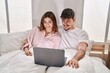 © Krakenimages.com - Mand and woman couple using laptop sitting on bed at bedroom