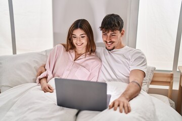 Poster - Mand and woman couple using laptop sitting on bed at bedroom