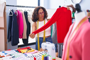 Sticker - Middle age woman tailor holding t shirt at clothing factory