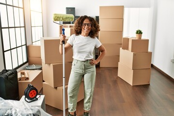 Canvas Print - Middle age hispanic woman smiling confident holding paint roller at new home