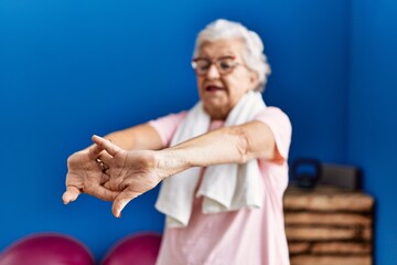 Wall Mural - Senior grey-haired woman wearing sportswear smiling confident standing at sport center