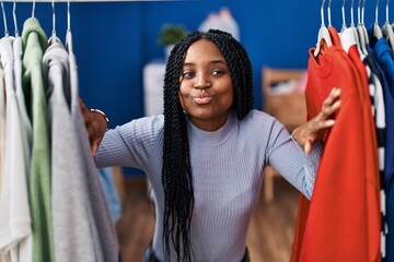 Canvas Print - African american woman searching clothes on clothing rack looking at the camera blowing a kiss being lovely and sexy. love expression.