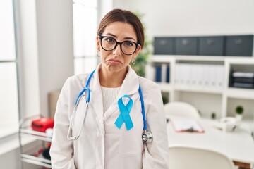 Wall Mural - Young brunette doctor woman wearing stethoscope at the clinic depressed and worry for distress, crying angry and afraid. sad expression.