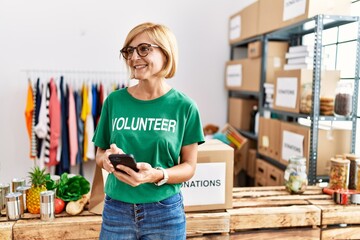 Sticker - Middle age blonde woman wearing volunteer uniform using smartphone at charity center