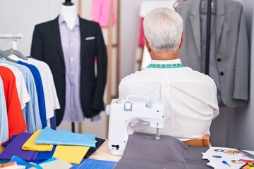 Sticker - Middle age man with grey hair dressmaker using sewing machine standing backwards looking away with crossed arms