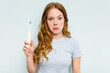© Asier - Young caucasian woman holding electric toothbrush isolated on blue background shrugs shoulders and open eyes confused.